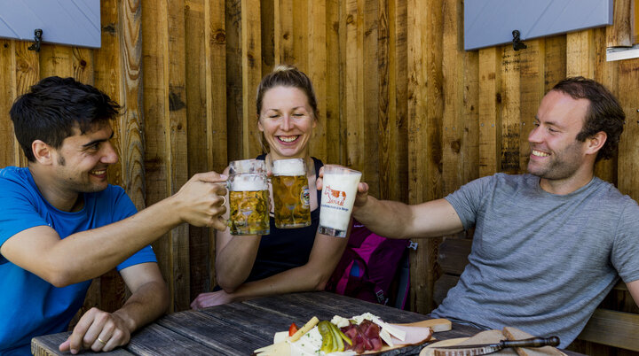 Auf der Hütte: Drei Personen stoßen mit Bierkrügen an | © DAV/Hans Herbig